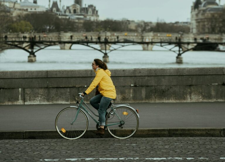 Une cycliste sur les quais de Seine à Paris. La cycliste porte un manteau jaune.